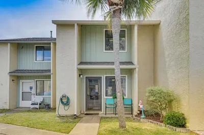 a house with a palm tree in front of it at The Wave PCB Townhome with Pools and Beach Access in Panama City Beach