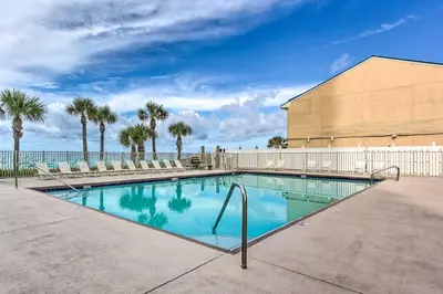 a swimming pool with palm trees and a building at The Wave PCB Townhome with Pools and Beach Access in Panama City Beach