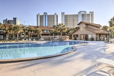 a large swimming pool with palm trees and buildings at The Wave PCB Townhome with Pools and Beach Access in Panama City Beach