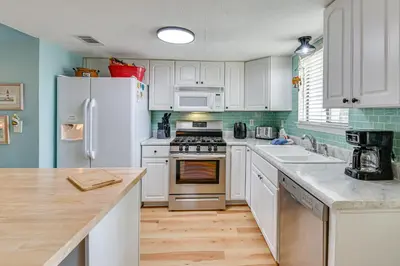 a kitchen with white cabinets and a white refrigerator at The Wave PCB Townhome with Pools and Beach Access in Panama City Beach