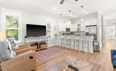 a living room with a kitchen and a bar with chairs at 17 Trigger Trail West in Panama City
