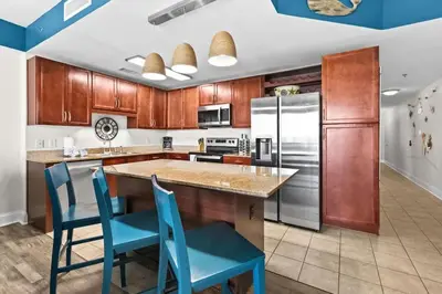 a kitchen with wooden cabinets and blue chairs at Laketown Wharf 1817 in Panama City Beach