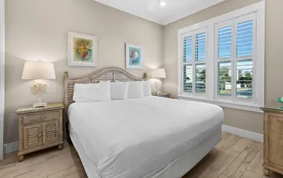 a bedroom with a large white bed and two windows at Blessing on the Beach in Panama City Beach