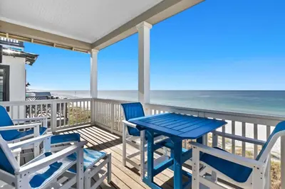 a table and chairs on a deck with the beach at Blessing on the Beach in Panama City Beach