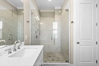 a white bathroom with a shower and a sink at Blessing on the Beach in Panama City Beach