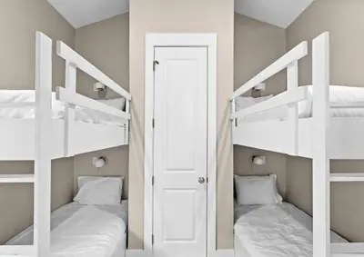 two white bunk beds in a room with a door at Blessing on the Beach in Panama City Beach