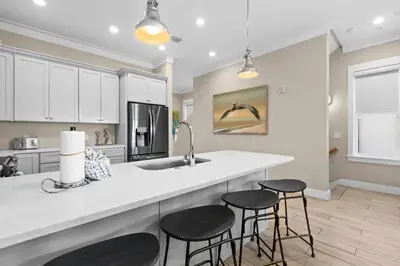 a kitchen with white cabinets and a counter with stools at Blessing on the Beach in Panama City Beach