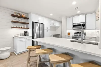 a kitchen with white cabinets and a counter with stools at Latitude 29 Unit 21 in Panama City Beach