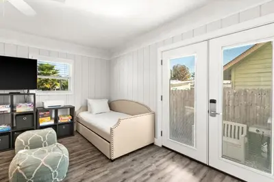a bedroom with a bed and a tv and a chair at Sandy Feet Escape in Panama City Beach