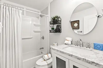 a white bathroom with a sink and a mirror at Sandy Feet Escape in Panama City Beach