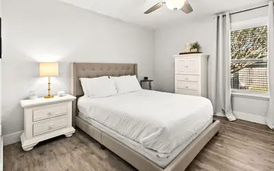 a white bedroom with a bed and a window at Sandy Feet Escape in Panama City Beach