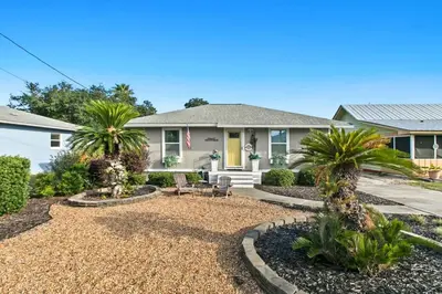 a home with palm trees in the front yard at Sandy Feet Escape in Panama City Beach