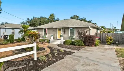 a house with a white fence in front of it at Sandy Feet Escape in Panama City Beach