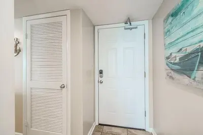 a white door in a hallway with a painting at One Seagrove Place 1101 in Santa Rosa Beach
