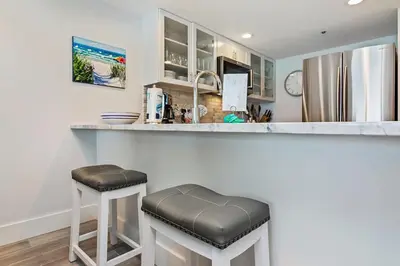 a kitchen with a counter with two stools at a bar at One Seagrove Place 0806 in Santa Rosa Beach