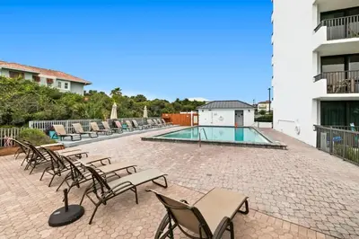a group of chairs and a swimming pool on a patio at One Seagrove Place 0802 in Santa Rosa Beach