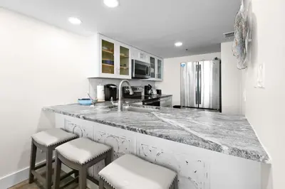 a kitchen with a marble counter top and stools at One Seagrove Place 0802 in Santa Rosa Beach