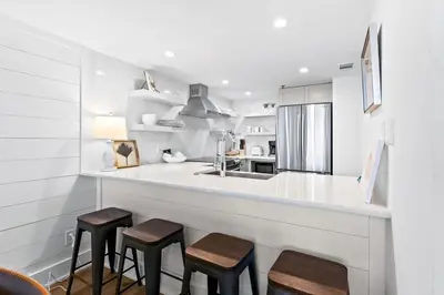 a kitchen with a counter with stools and a sink at One Seagrove Place 0906 in Santa Rosa Beach