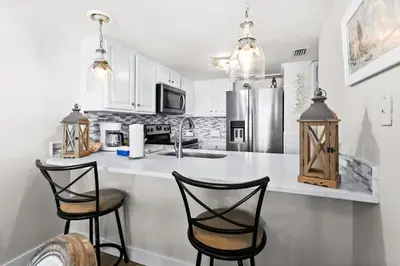 a white kitchen with two chairs and a counter at One Seagrove Place 0704 in Santa Rosa Beach