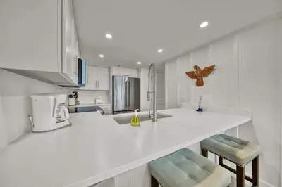 a kitchen with a white counter and two stools at One Seagrove Place 0804 in Santa Rosa Beach