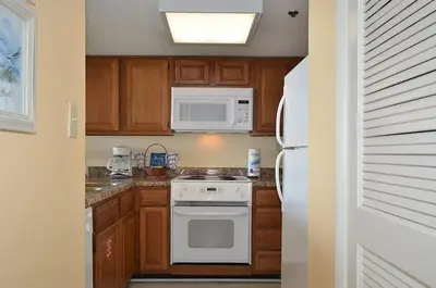 a kitchen with white appliances and wooden cabinets at One Seagrove Place 1001 in Santa Rosa Beach