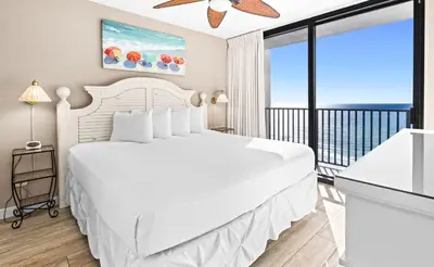 a bedroom with a white bed and a balcony at One Seagrove Place 1004 in Santa Rosa Beach