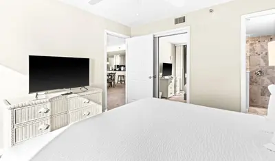 a white bedroom with a flat screen tv on a dresser at One Seagrove Place 1208 in Santa Rosa Beach
