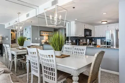 a kitchen and dining room with a white table and chairs at One Seagrove Place 0902 in Santa Rosa Beach