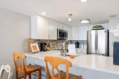 a kitchen with white cabinets and a stainless steel refrigerator at One Seagrove Place 1303 in Santa Rosa Beach