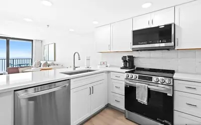 a kitchen with white cabinets and a black stove top oven at One Seagrove Place 1203 in Santa Rosa Beach