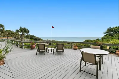 a wooden deck with chairs and tables and the ocean at One Seagrove Place 1203 in Santa Rosa Beach