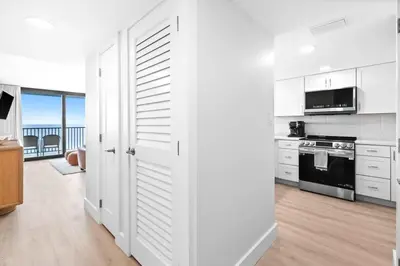 a kitchen with white cabinets and an open door at One Seagrove Place 1203 in Santa Rosa Beach