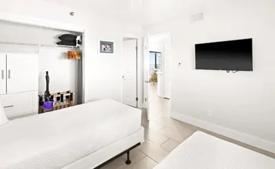 a white bedroom with a bed and a flat screen tv at One Seagrove Place 1503 in Santa Rosa Beach