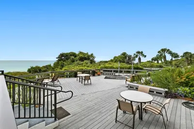 a deck with tables and chairs and the ocean at One Seagrove Place 1503 in Santa Rosa Beach