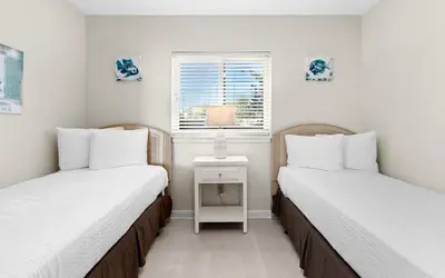 two twin beds in a room with a window at One Seagrove Place 0107 in Santa Rosa Beach