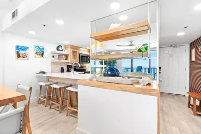 a kitchen with white walls and a counter with a table at One Seagrove Place 1106 in Santa Rosa Beach