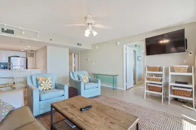a living room with two blue chairs and a table at One Seagrove Place 0201 in Santa Rosa Beach