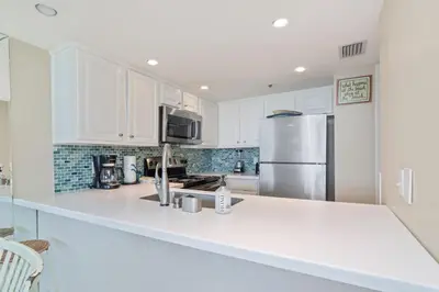 a kitchen with white cabinets and a stainless steel refrigerator at One Seagrove Place 0201 in Santa Rosa Beach