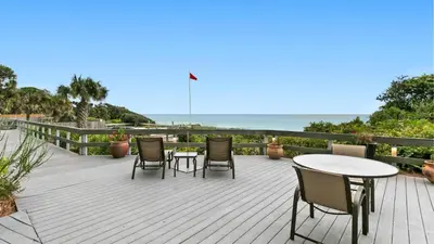 a wooden deck with chairs and tables and the ocean at One Seagrove Place 0205 in Santa Rosa Beach