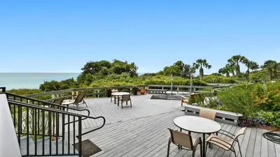 a deck with tables and chairs and the ocean at One Seagrove Place 0205 in Santa Rosa Beach