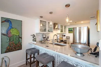 a kitchen with a sink and a counter with chairs at One Seagrove Place 0205 in Santa Rosa Beach