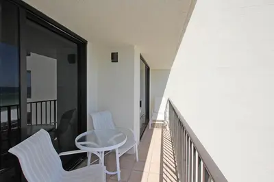 a balcony with two white chairs and a table at One Seagrove Place 0403 in Santa Rosa Beach