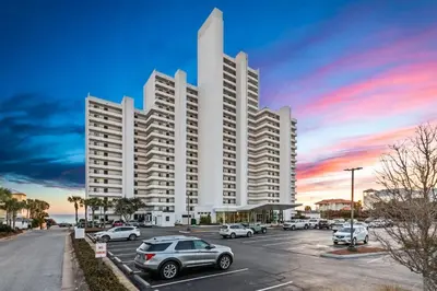 a large white building with cars parked in a parking lot at One Seagrove Place 0403 in Santa Rosa Beach