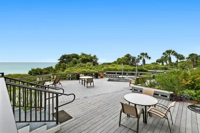 a deck with tables and chairs and the ocean at One Seagrove Place 0403 in Santa Rosa Beach