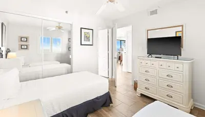 a white bedroom with a bed and a television at One Seagrove Place 1508 in Santa Rosa Beach