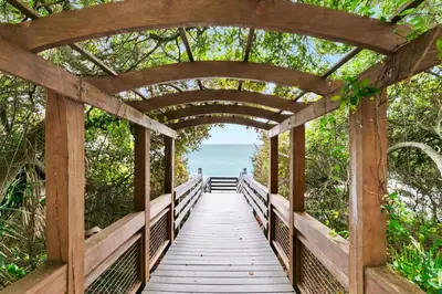 a wooden bridge over a boardwalk leading to the ocean at One Seagrove Place 1906 in Santa Rosa Beach