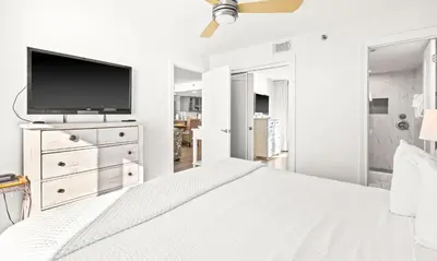 a white bedroom with a bed and a flat screen tv at One Seagrove Place 1706 in Santa Rosa Beach