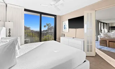 a white bedroom with a large bed and a television at One Seagrove Place 0105 in Santa Rosa Beach