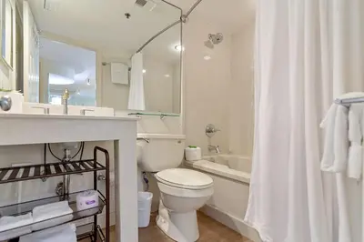 a white bathroom with a toilet and a sink and a tub at One Seagrove Place 0105 in Santa Rosa Beach
