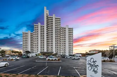 a large white building with cars parked in a parking lot at One Seagrove Place 1206 in Santa Rosa Beach